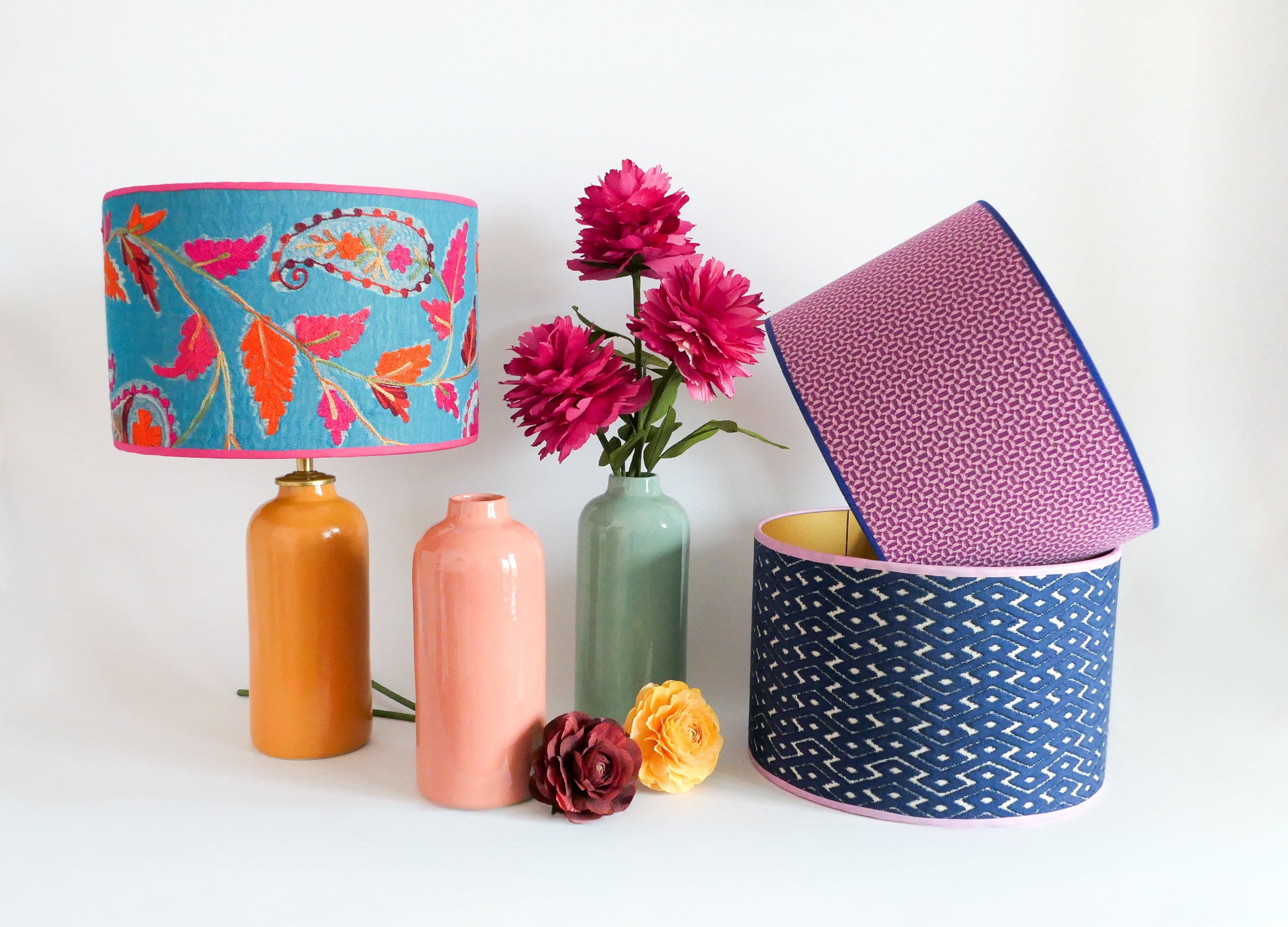 Colorful handmade lampshades and vases with paper flowers on a white background
