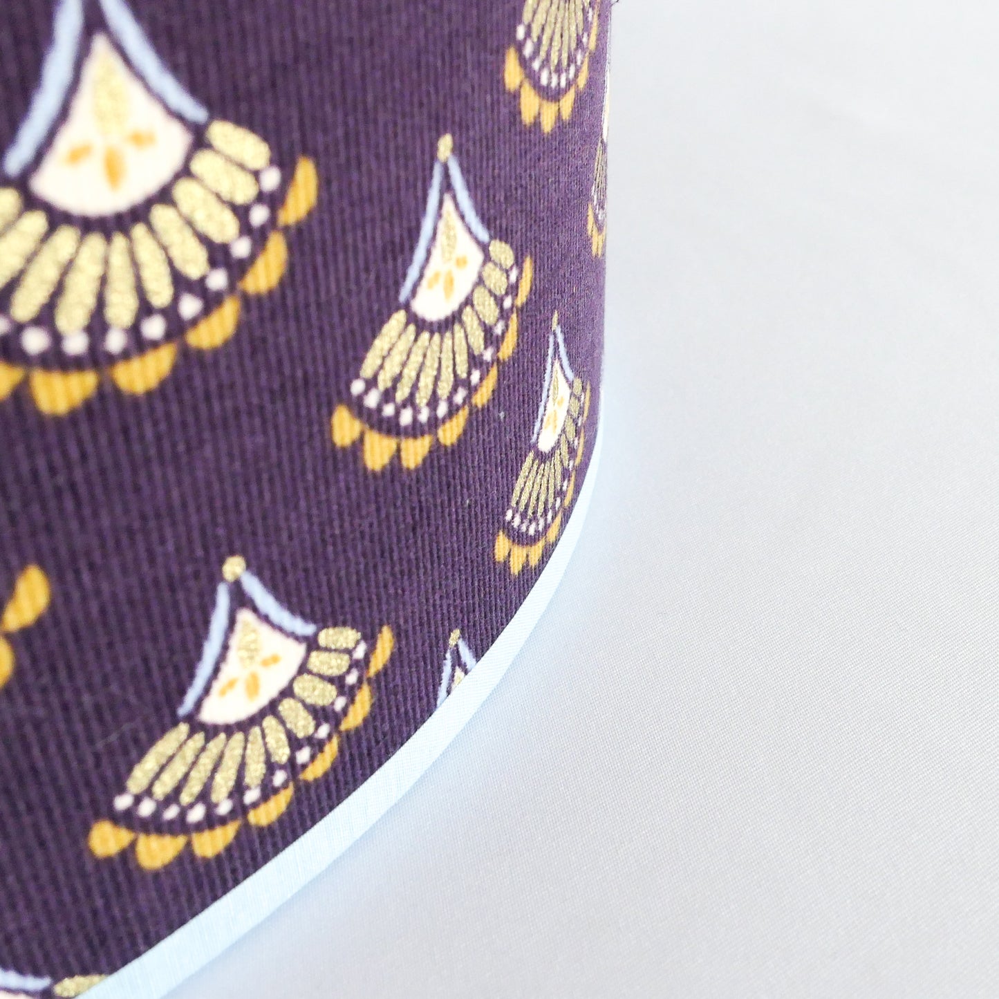 Close-up of a purple fabric with yellow geometric patterns and a light blue rim