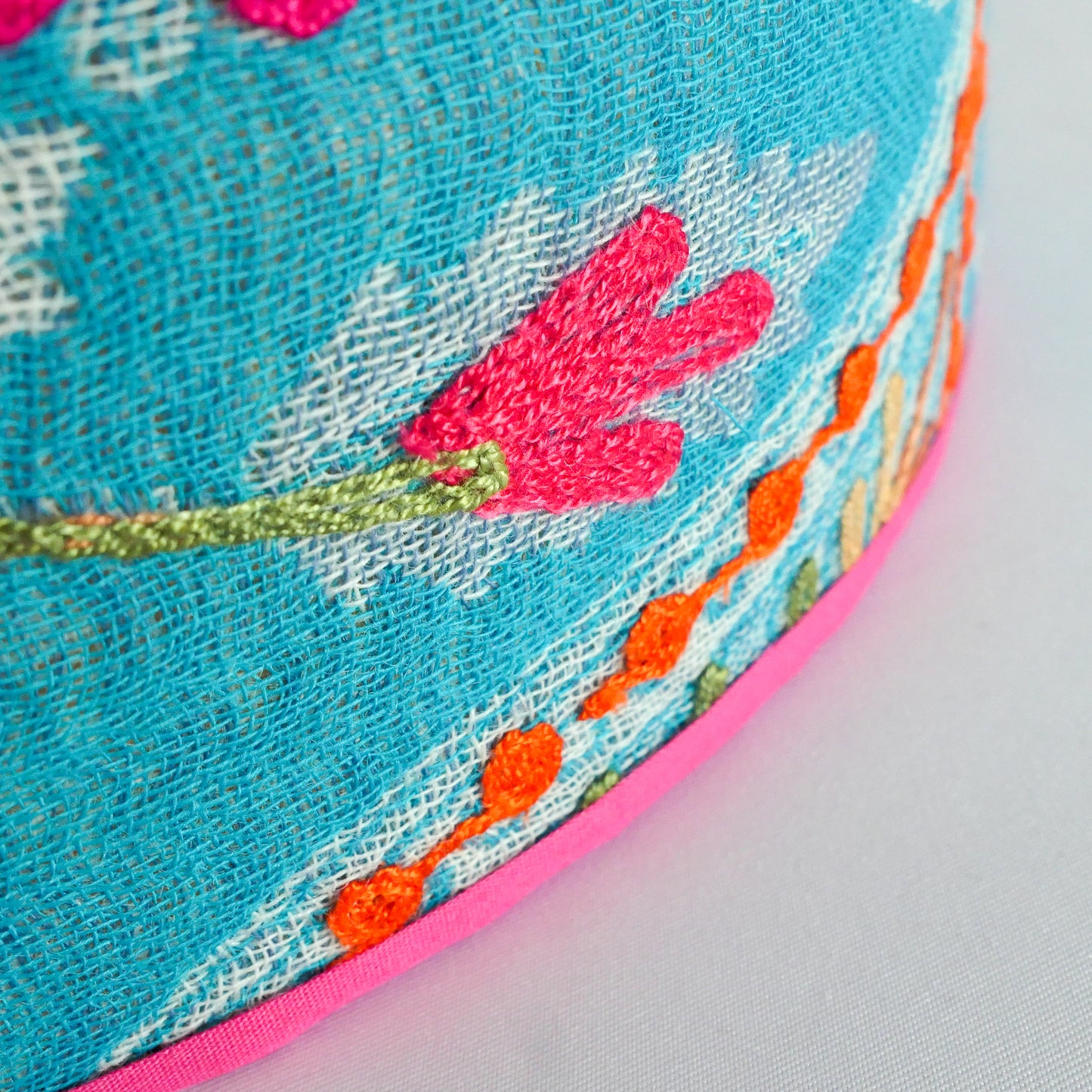 Close-up of a blue embroidered fabric with floral patterns and a pink rim.