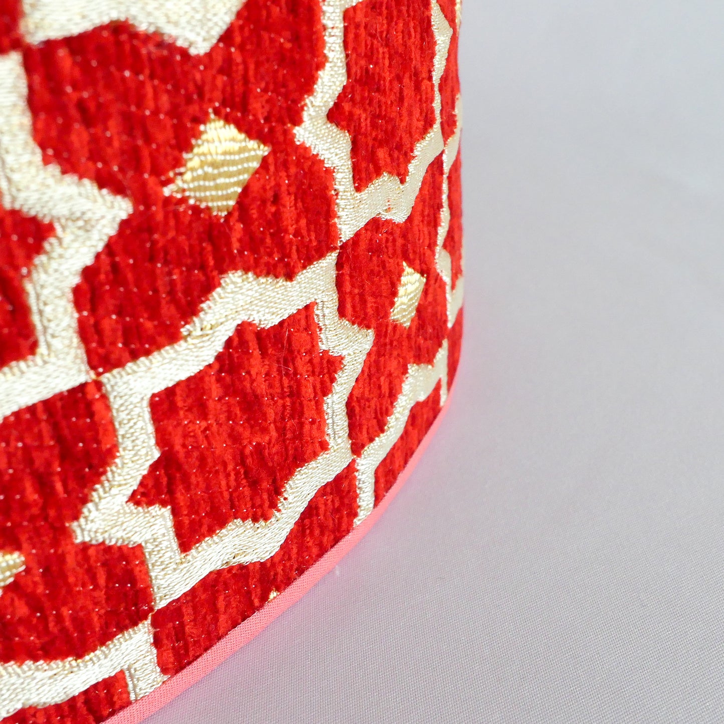 Close-up of a red and gold textured lampshade on a white background