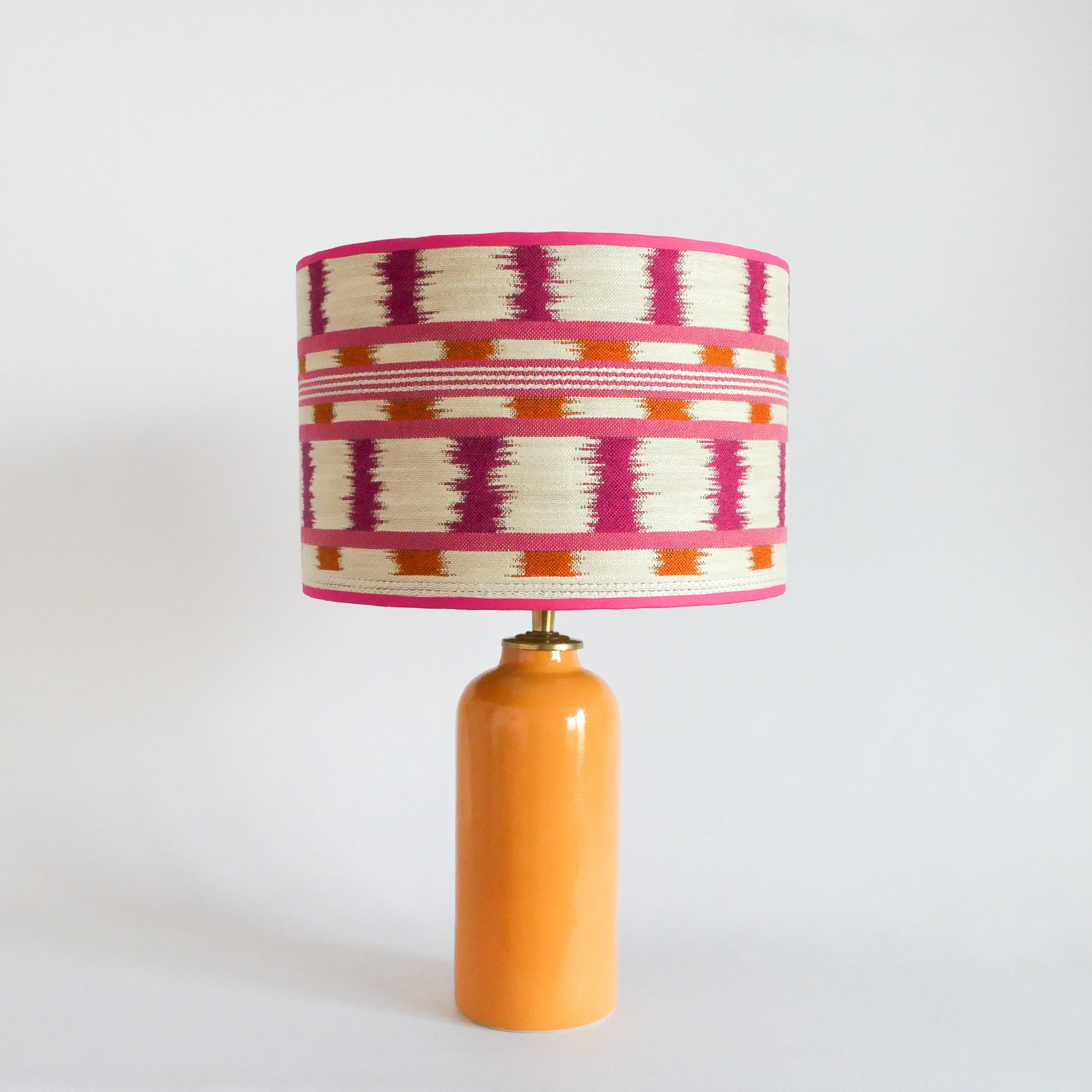 Ceramic table lamp with a colorful striped lampshade and a warm yellow base