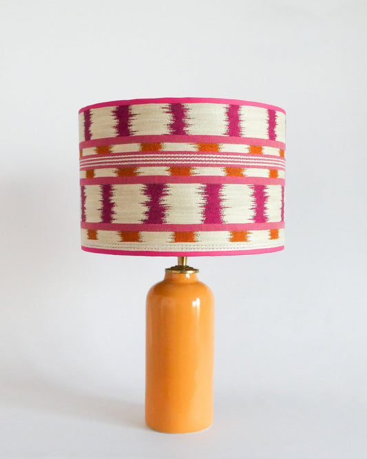 Ceramic table lamp with a colorful striped shade and a warm yellow base on a white background
