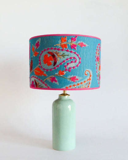 Ceramic table lamp with a blue embroidered shade with floral patterns on a mint green lamp base