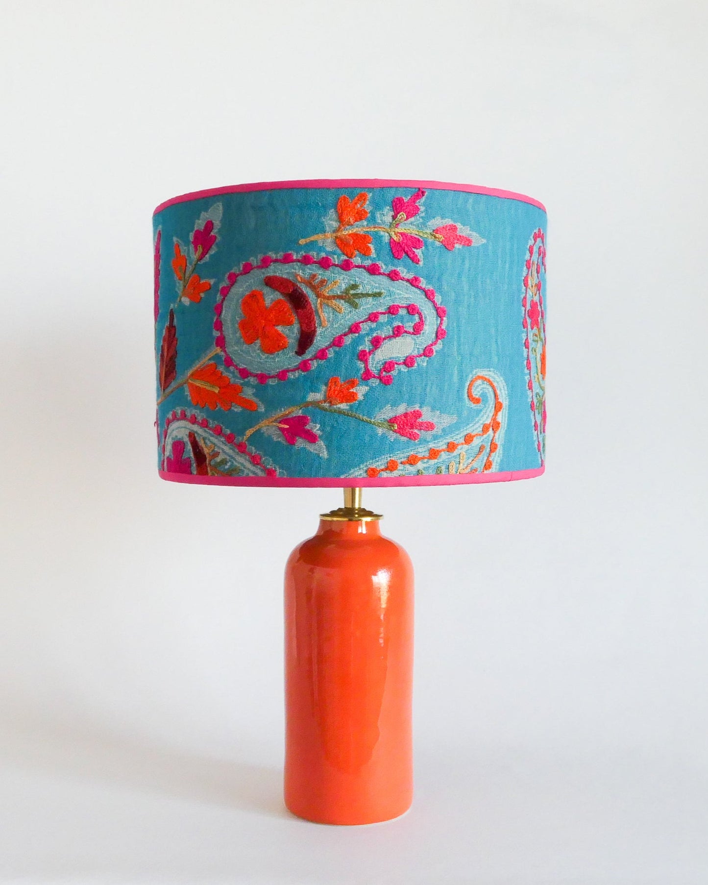 Ceramic table lamp with a blue embroidered shade with floral patterns on an orange lamp base