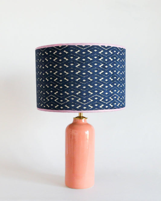 Ceramic table lamp with a pastel peach base and a blue patterned shade on a white background