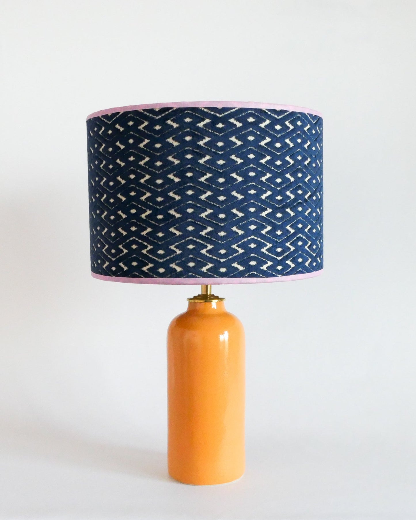 Ceramic table lamp with a blue patterned shade and a warm yellow base on a white background