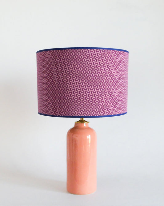 Ceramic table lamp with a pastel pink base and a patterned purple shade on a white background