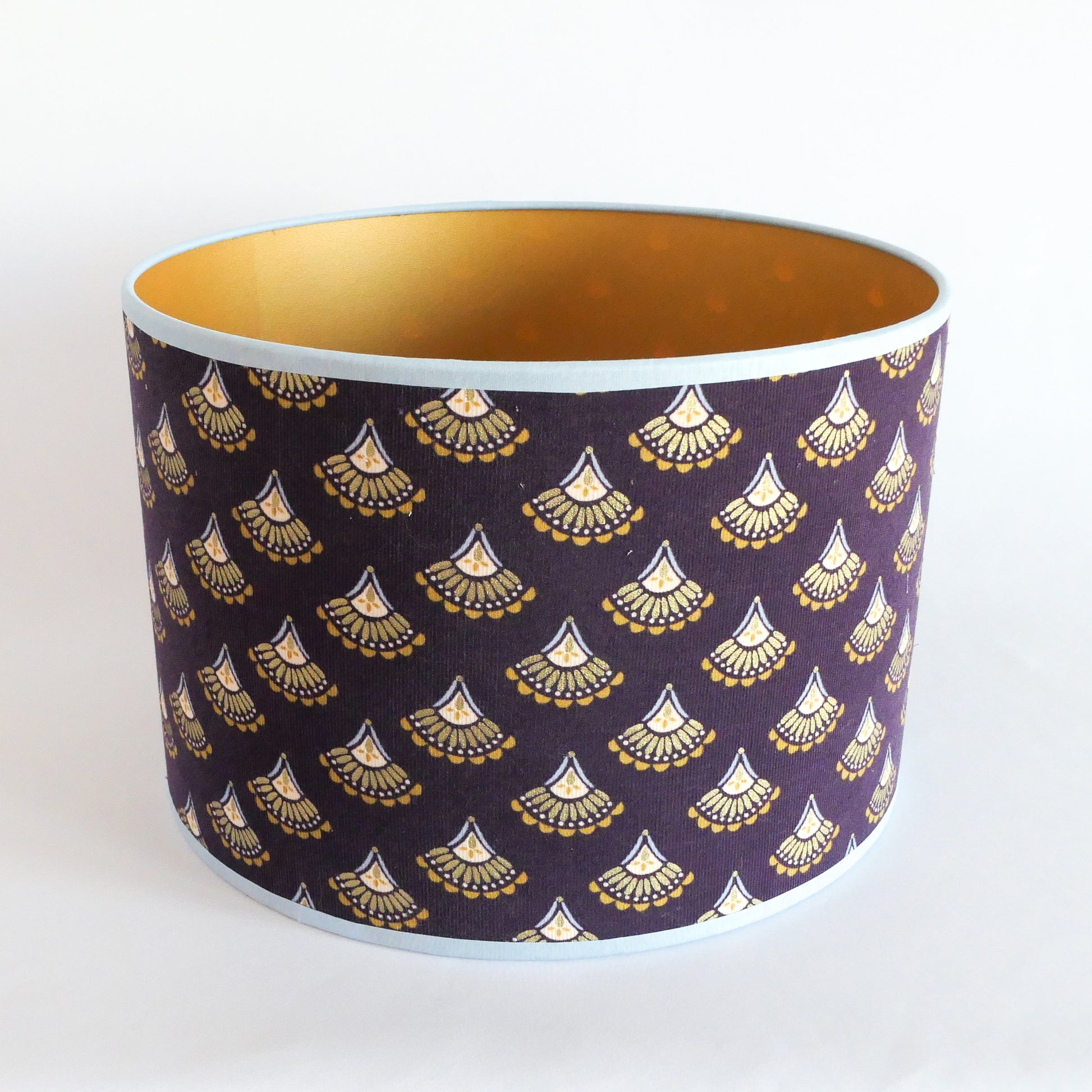 Top view of a purple lampshade featuring gold patterns with a gold interior and a light blue rim.