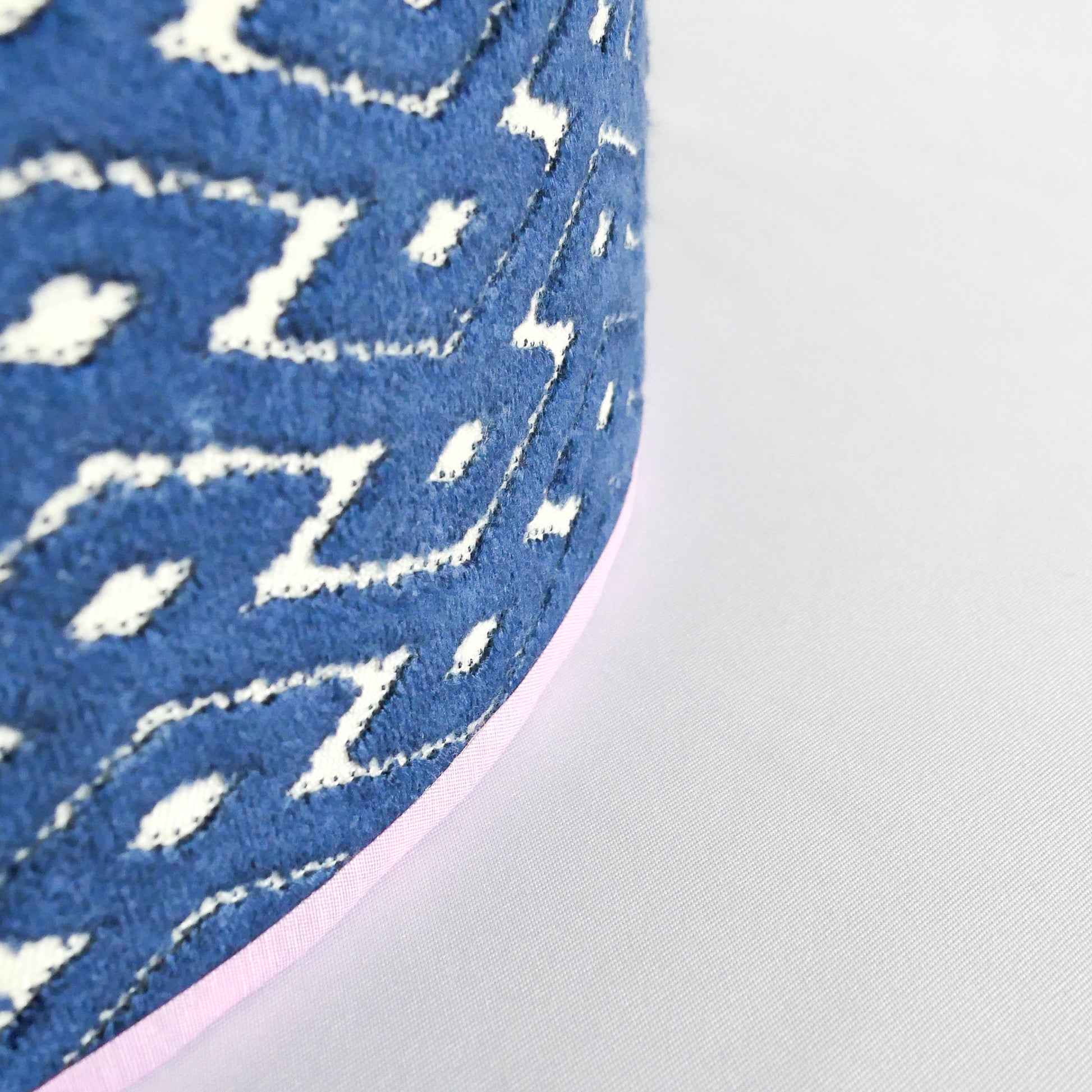 Close up of a blue patterned lampshade with a lila rim.