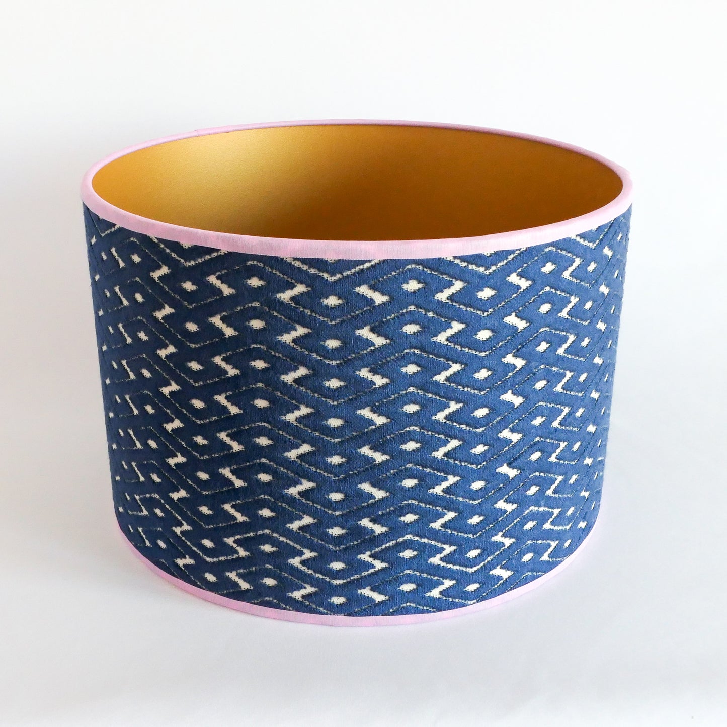 Top view of a blue patterned lampshade with a gold interior and a lila rim