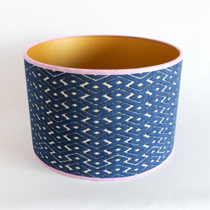 Top view of a blue patterned lampshade with a gold interior and a lila rim
