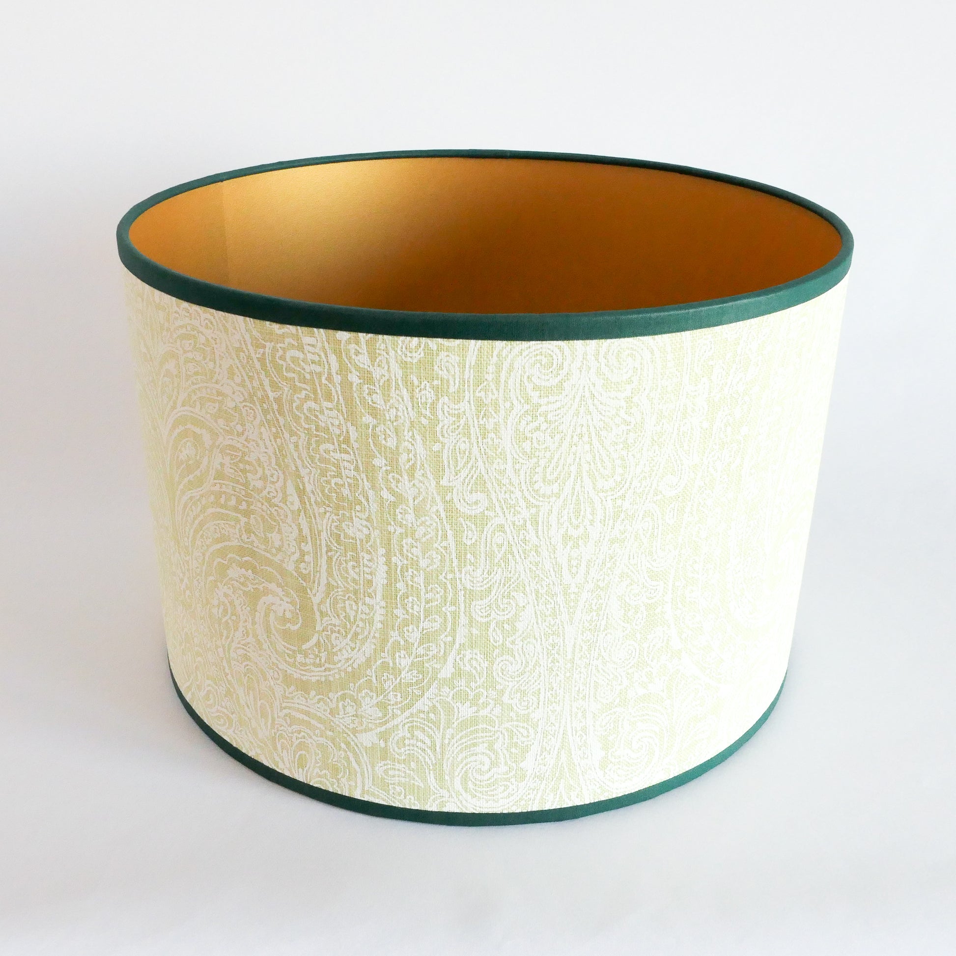 Top view of a lampshade with a light green pattern, a gold interior and a dark green rim