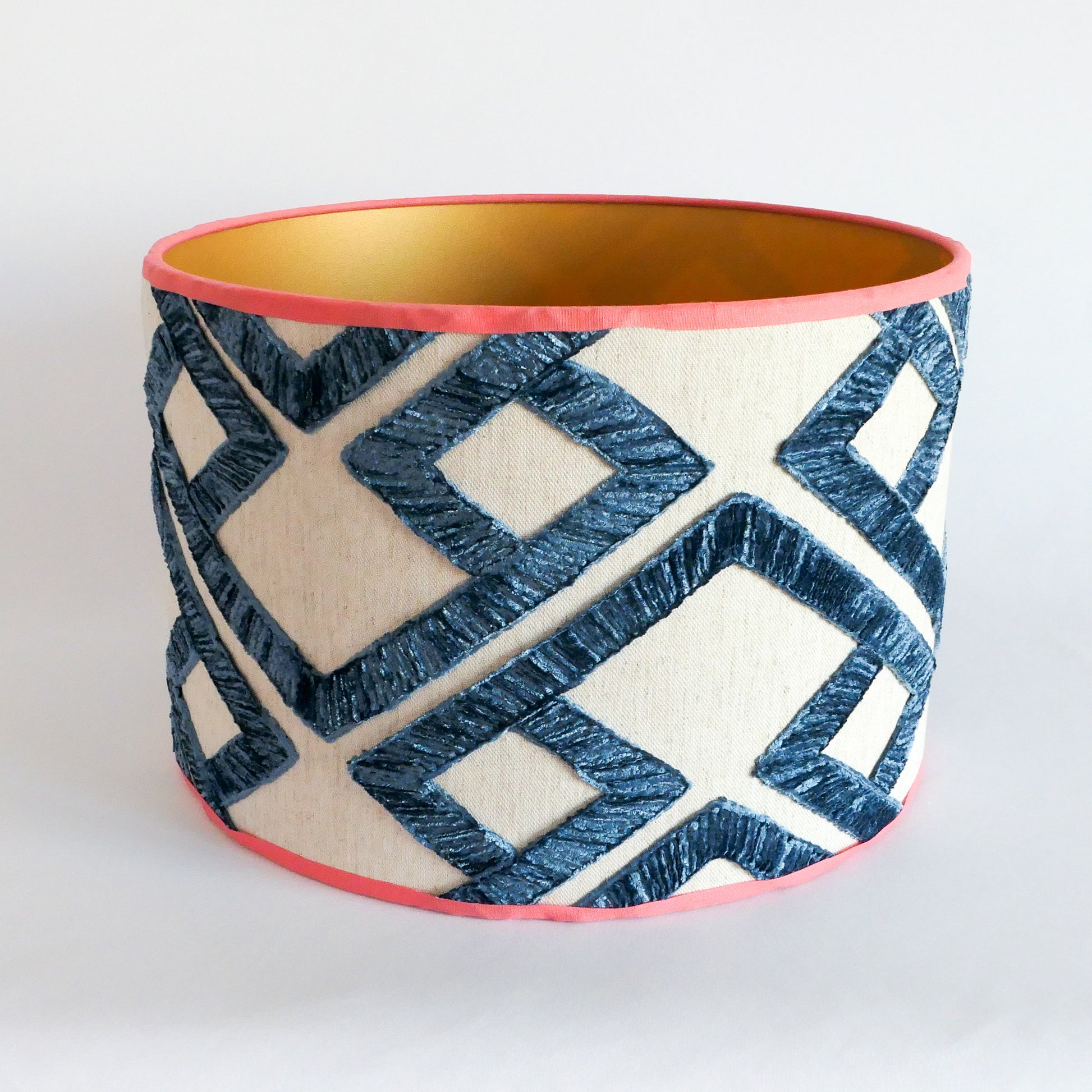 Top view of a lampshade with a geometric pattern, an orange rim and gold interior.