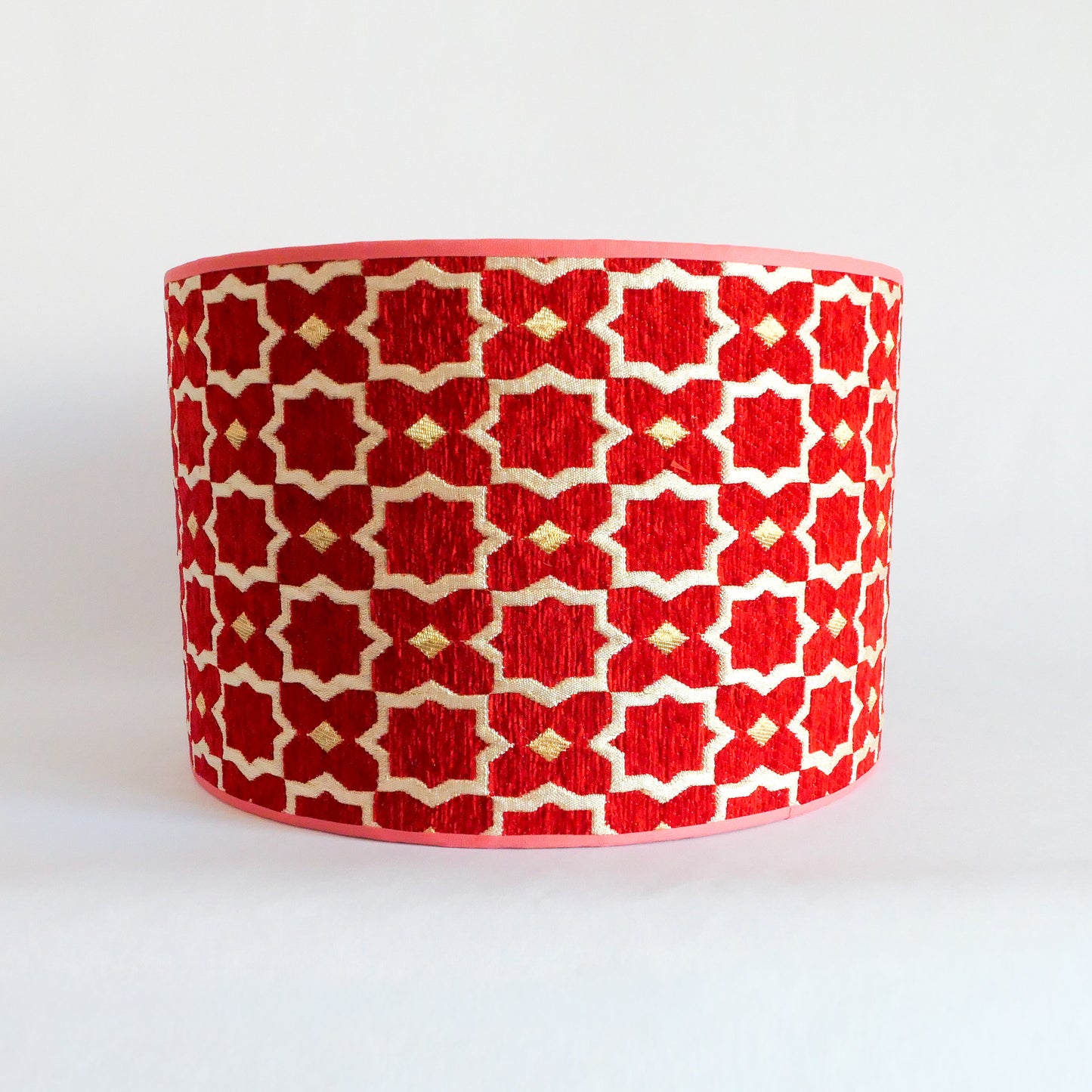 Front view of a red and white patterned lampshade on a white background