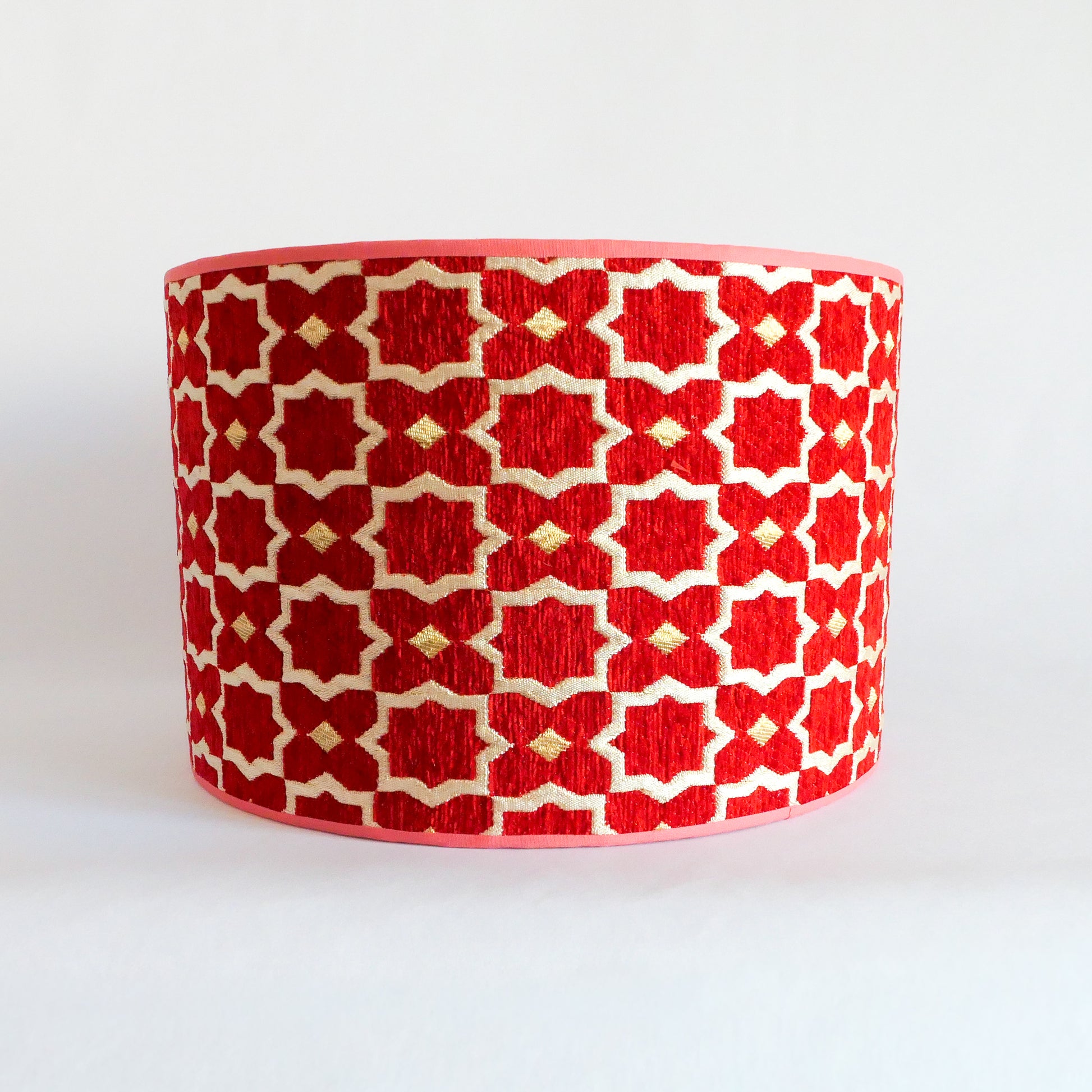 Front view of a red and white patterned lampshade on a white background