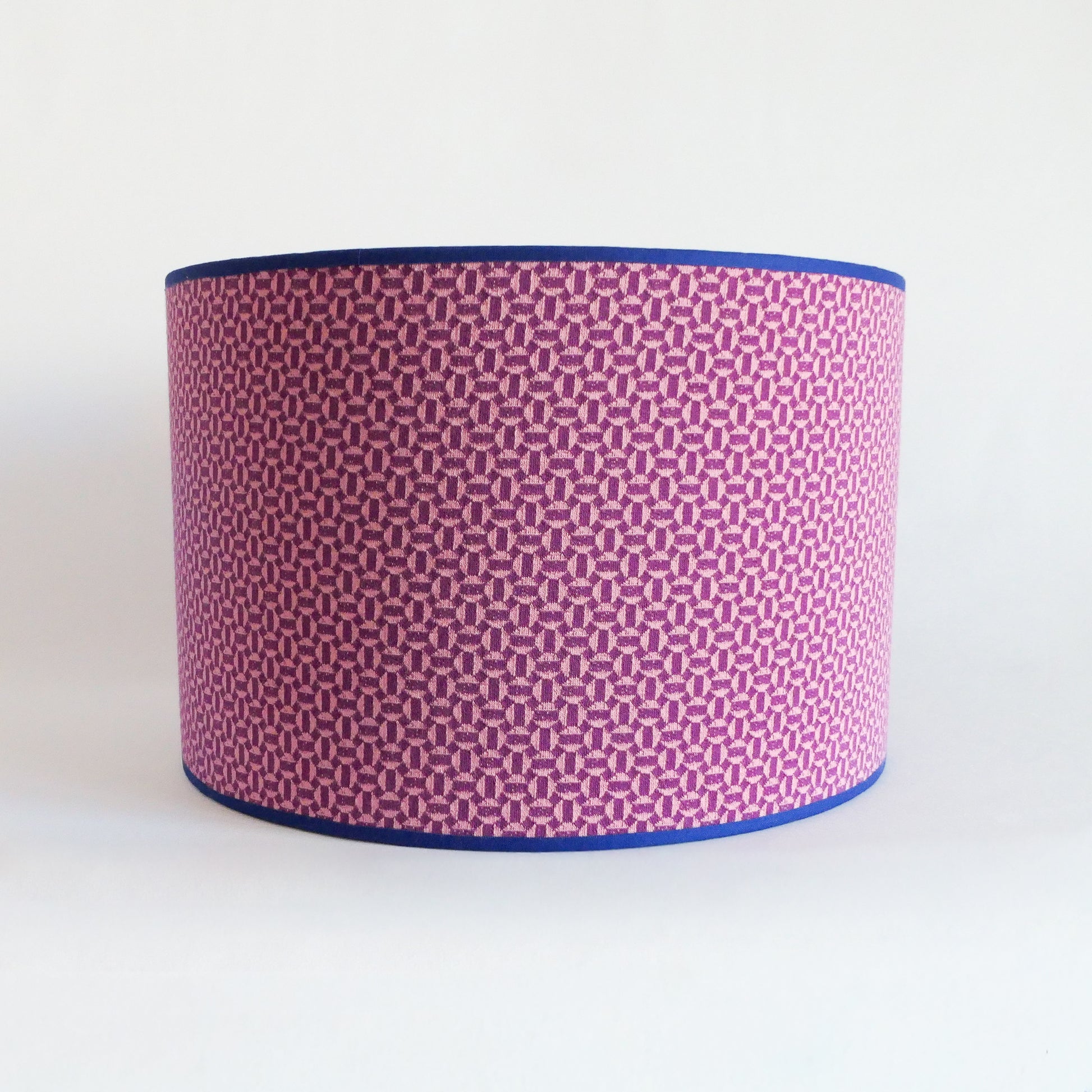 Front view of a lampshade with a pink geometric pattern and blue rim on a white background