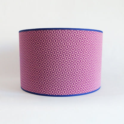 Front view of a lampshade with a pink geometric pattern and blue rim on a white background