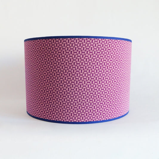 Front view of a lampshade with a pink geometric pattern and blue rim on a white background