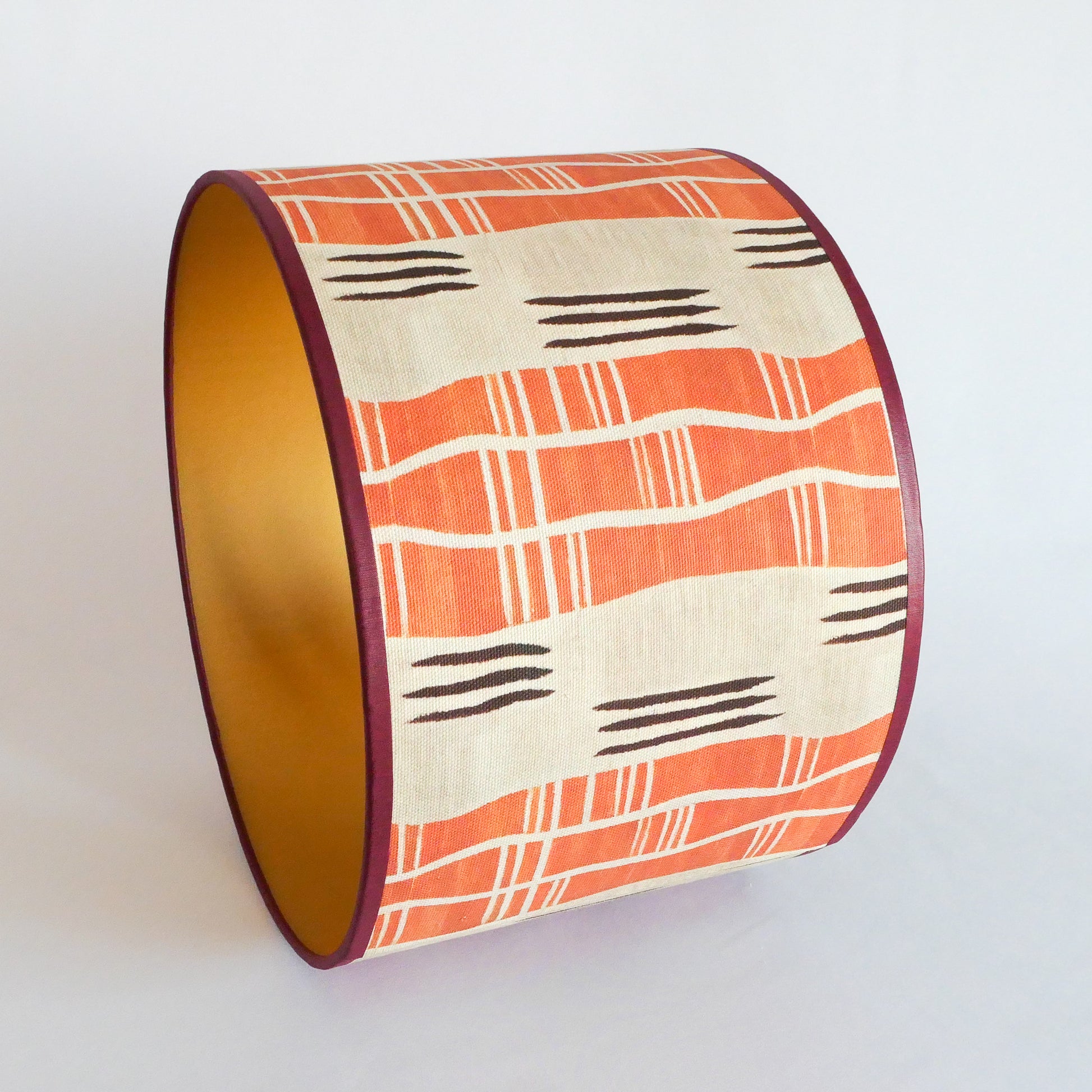 Side view of a lampshade with an African pattern with a golden interior on a white background