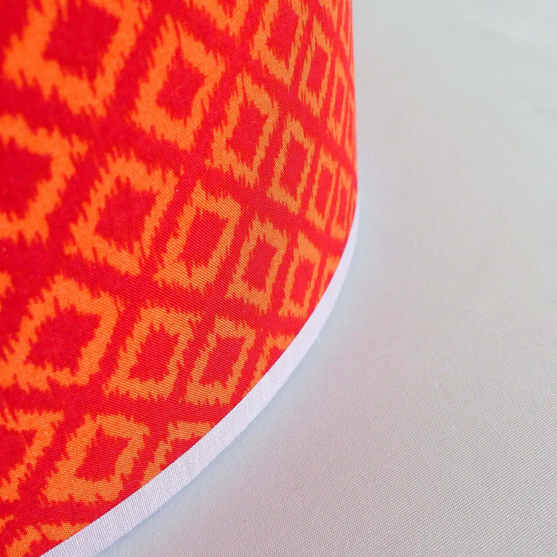 Close-up of a red and orange geometric patterned lampshade on a white background