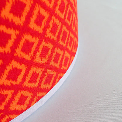 Close-up of a red and orange geometric patterned lampshade on a white background