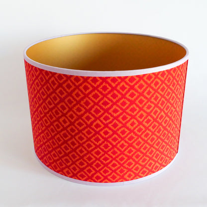 Top view of a red patterned lampshade with gold interior on a white background